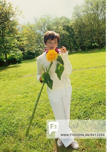 Frau mit Sonnenblume auf einer Wiese