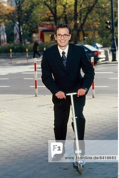Ein junger Geschäftsmann auf seinem Kickboard