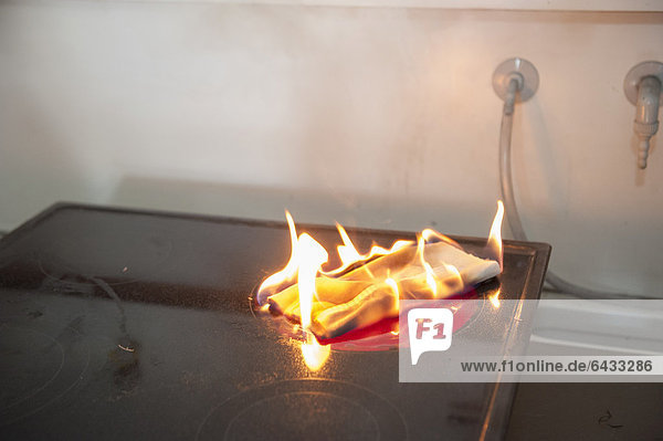 Towel lying on a switched on hot plate demonstrating fire causes such as kitchen fires Stuttgart Baden-Wuerttemberg Germany Europe