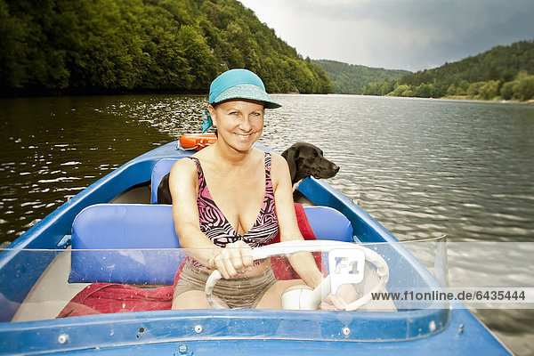 Woman driving an electric boat  a dog standing at the back