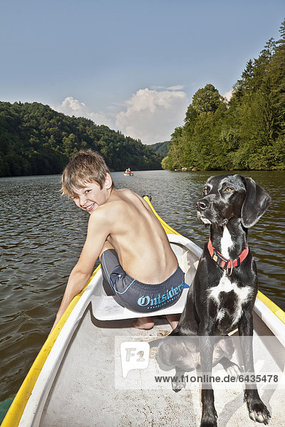 Boy sitting in a canoe with his hunting dog  mongrel