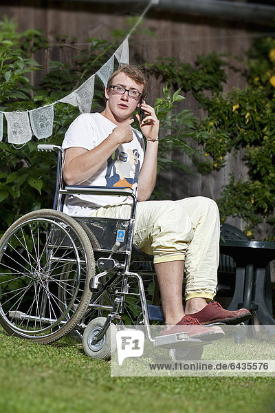 Teenager sitting in a wheelchair speaking on a mobile phone