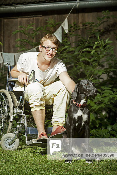 Teenager sitting in a wheelchair  with a companion dog  therapy dog