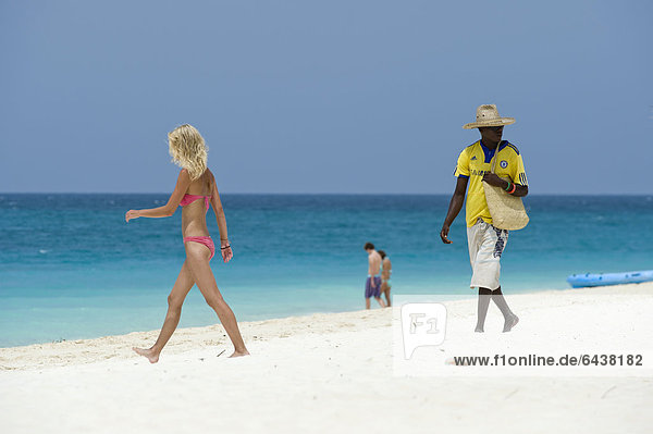 Souvenir seller and female holidaymaker on the beach of Kendwa Rocks  north coast of Zanzibar  Tanzania  Africa