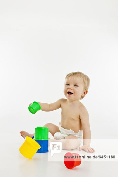 A baby boy playing with plastic cups