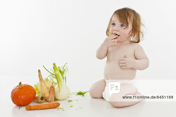 Ein kleines Mädchen neben Gemüse