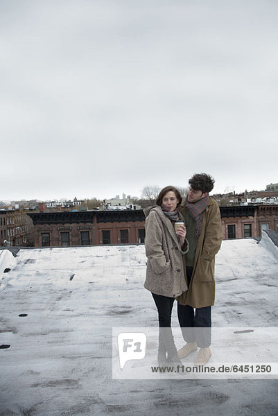 A young couple standing on a roof in winter