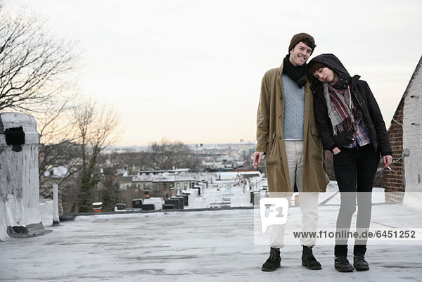 A young couple standing on a roof in winter  smoking cigarettes