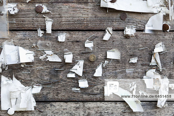Detail von Heftklammern  Heftzwecken und gerissenem Papier an einer Holzwand