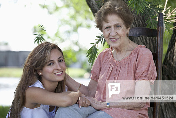 Porträt einer älteren Frau und einer jungen Frau  die zusammen im Freien sitzen.