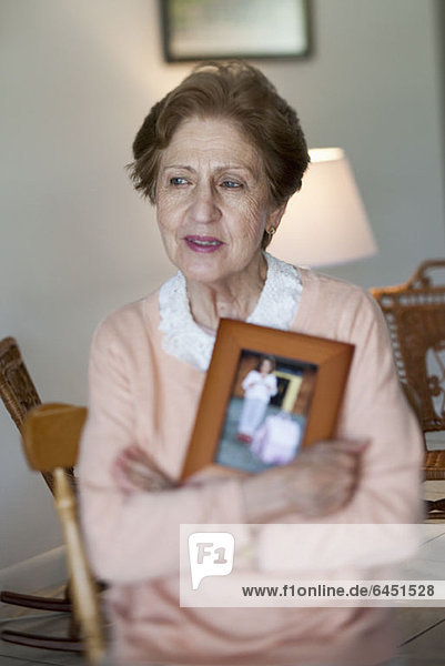 A senior woman holding a picture frame