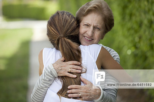 Eine ältere Frau  die eine junge Frau umarmt.