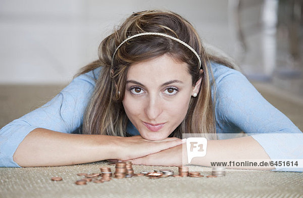 Eine Frau auf dem Boden liegend mit Stapeln von US-Münzen.