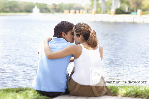 Ein liebevolles Paar beim Küssen am See  Rückansicht
