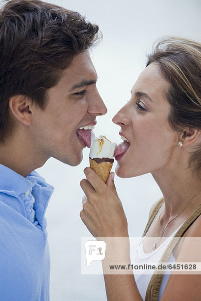 Ein junges Paar  das sich eine Eistüte teilt.