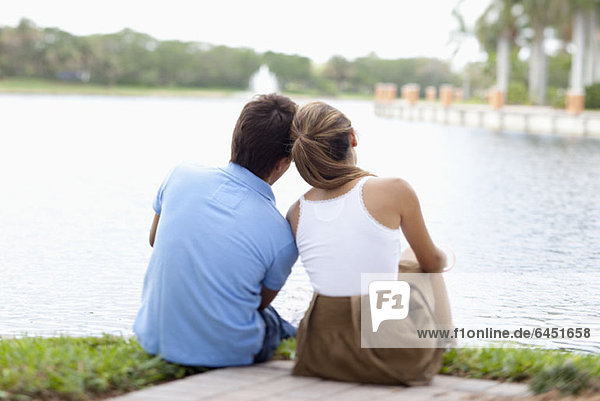 Ein Paar sitzt am See  Rückansicht