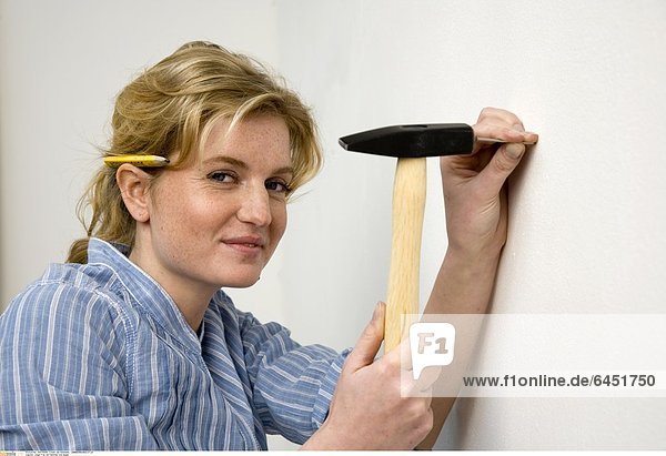 Junge Frau mit Hammer und Nagel