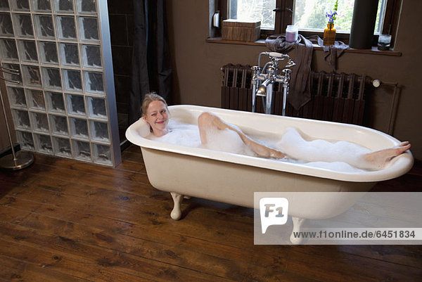 A woman taking a bubble bath and winking playfully