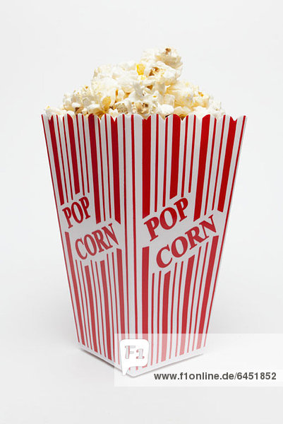 Studioaufnahme einer rot gestreiften Schachtel Popcorn mit aufgedrucktem Popcorn