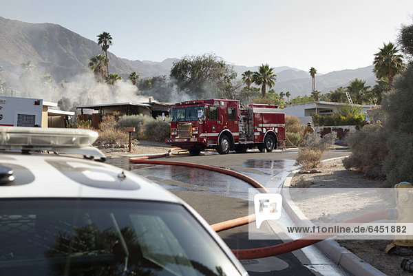 Ein Polizeiauto und ein Feuerwehrauto am Tatort eines brennenden Hauses in einem Vorort