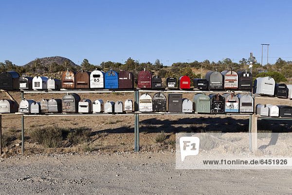 Rows of mailboxes next to a dirt road in a desert