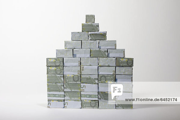 Fünf Euro-Banknoten in rechteckige Schachteln gefaltet und zu einer Pyramide gestapelt