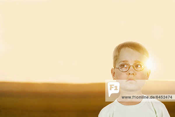 Porträt eines Jungen auf einem Feld bei Sonnenuntergang