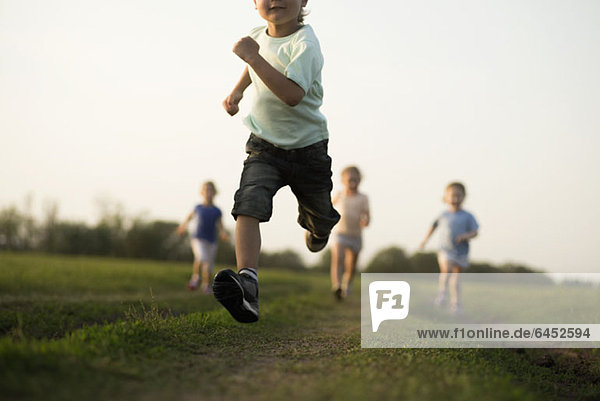 Low view of a boy running in a field with other children behind