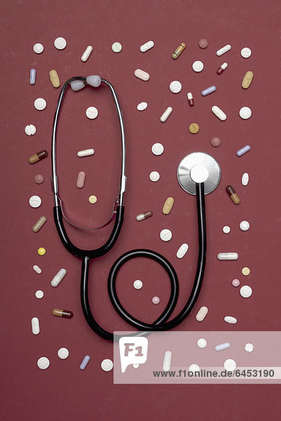Ein Stethoskop  das zwischen verschiedenen Pillen liegt.