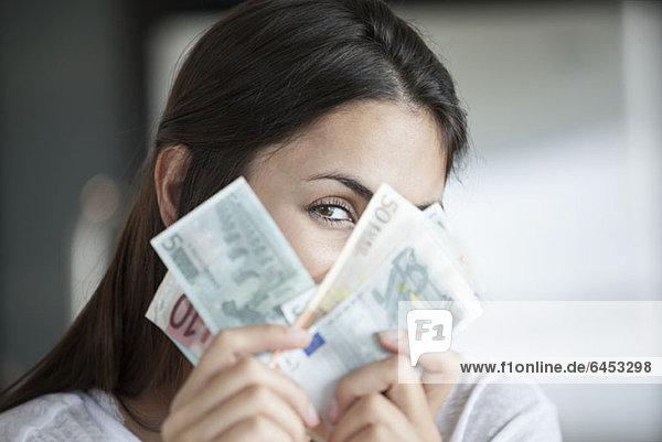 Frau schaut hinter die Euro-Banknoten