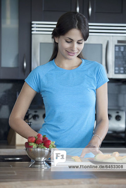 Frau beim Melonenschneiden in der Küche
