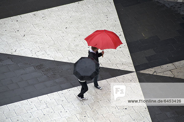 Zwei Fußgänger mit Regenschirmen