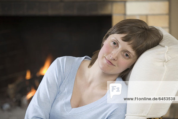 A serene young woman sitting near a roaring fire