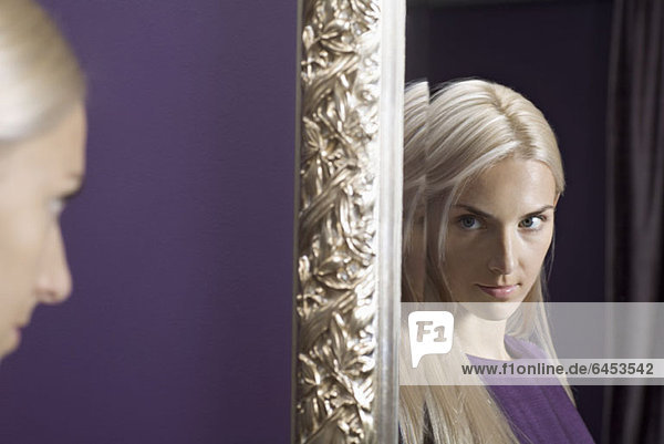 Eine schöne junge Frau  die auf ihr Spiegelbild starrt.
