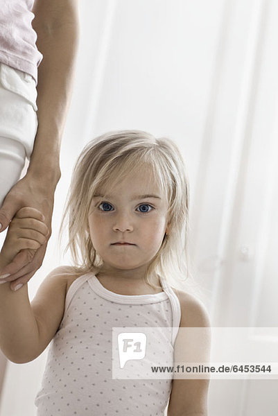 Ein junges Mädchen hält die Hand ihrer Mutter und starrt in die Kamera.