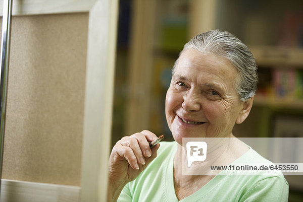 Eine fröhliche Seniorenfrau mit einem Pinsel