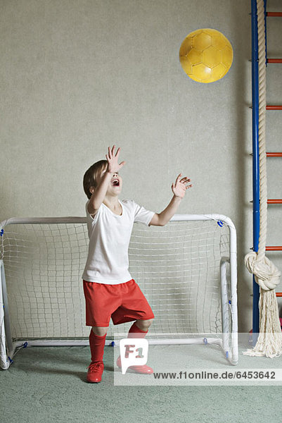 Ein Junge verteidigt ein Tor  während ein Ball auf ihn zufliegt.