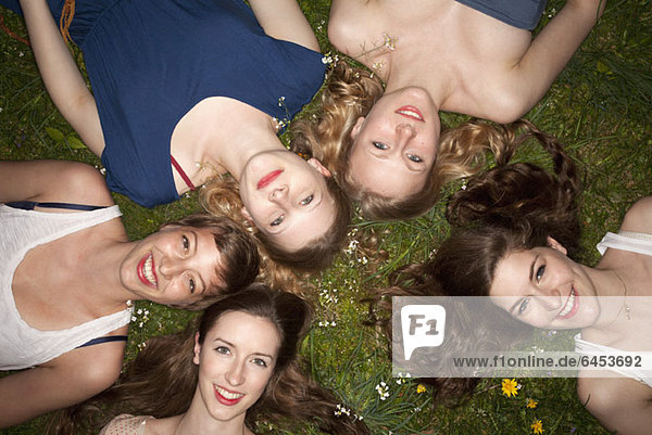 Fünf fröhliche Freundinnen liegen im Gras  Kopf und Schultern.