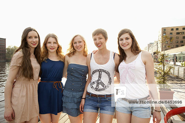 Five cheerful young female friends standing a row  Spree River  Berlin  Germany