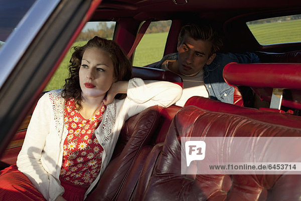 A rockabilly woman and man sitting in a vintage car