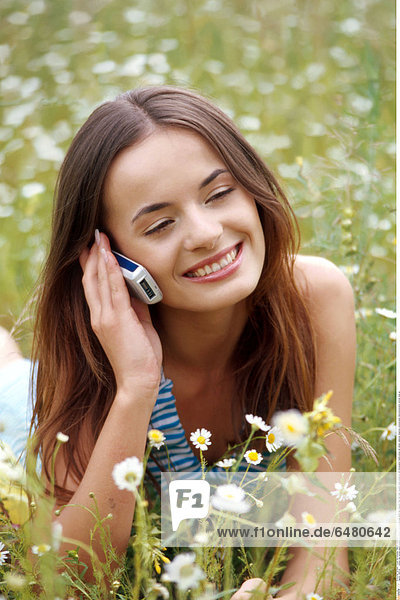 1228742 outdoor day summer people woman girl young 20-25 brunette long haired hair meadow field rest relax vacation smile smiling lie talk conversation mobile phone cell cellular cellphone telephone communication telecommunication vertical close up