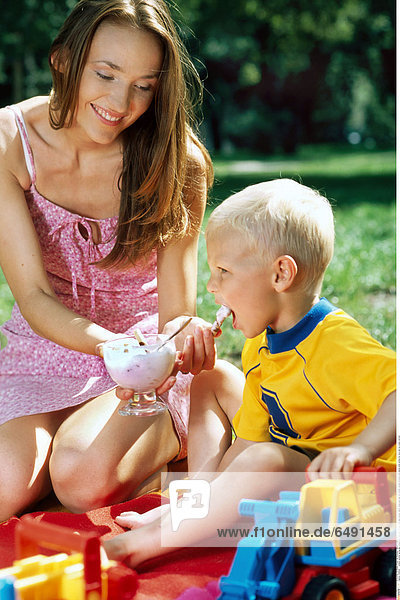 1236502 outdoor summer spring day people son child boy 0-5 fair rest relax blouse yellow dress pink play fun mother woman brunette long haired smile smiling toy toys eat ice cream vertical
