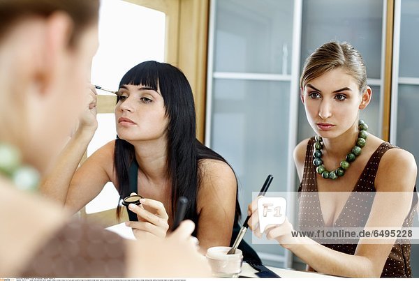 1241717 indoor flat bathroom mirror people woman women young 20-25 girl girls brunette fringe long haired blonde sister sisters friend friends friendship dress brown blue portrait close up smile smiling smile smiling horizontal make up beauty care hold mascara