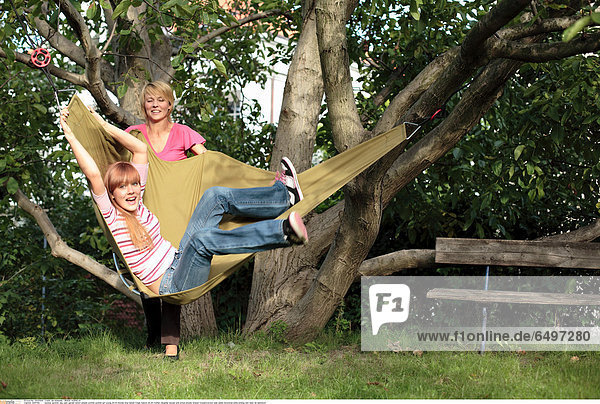 1244764 outdoor summer day park garden bench people woman women girl young 20-25 blonde long haired fringe mature 40-45 mother daughter blouse pink stripe stripes striped trousers brown jean jeans horizontal smile smiling rest relax lie hammock