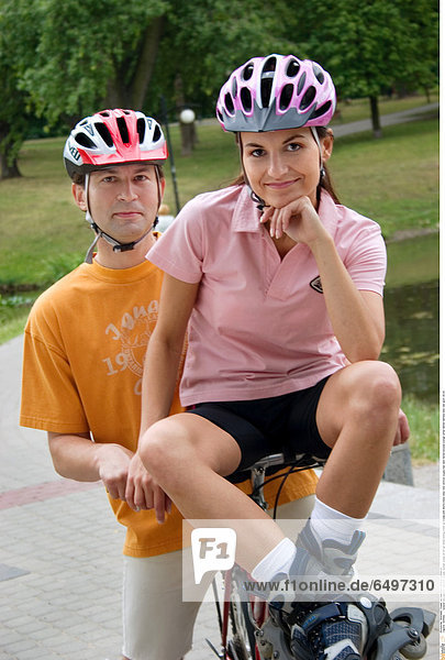 1245082 outdoor day summer vacation people woman young 20-25 girl smile smiling close up blouse pink shorts black relax rest vertical couple man dark haired blouses orange white helmet helmets bike ride sport 25-30