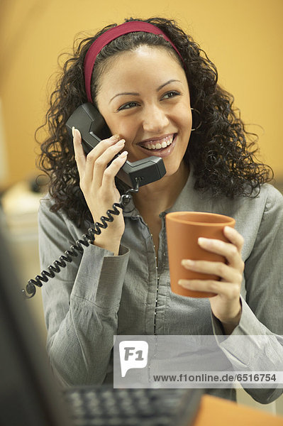 Young businesswoman drinking coffee and talking on the phone