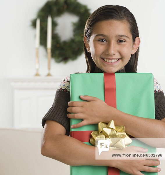 Hispanic girl holding gift and smiling