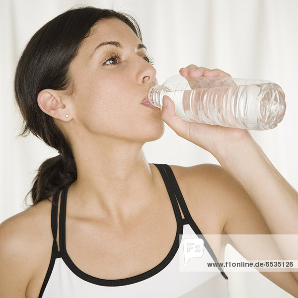Hispanic woman drinking bottled water