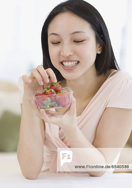 Asian woman holding bowl of strawberries