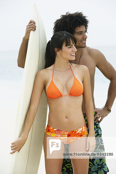 South American couple holding surfboard